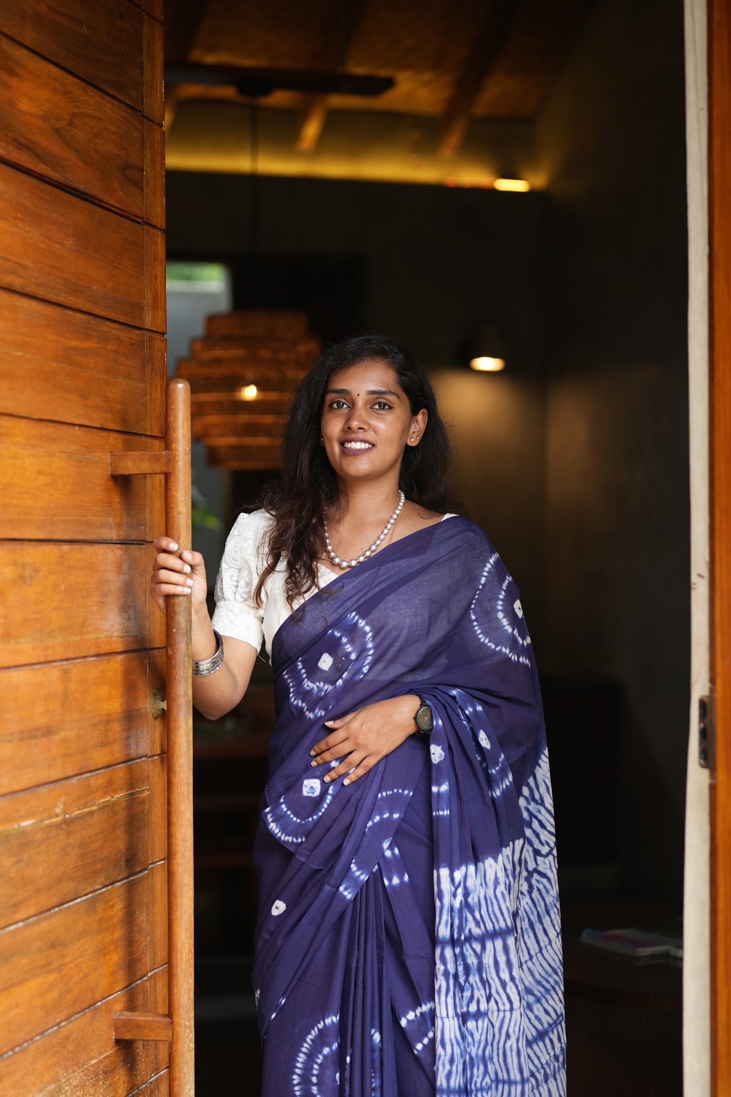 Woman in a blue saree standing in a doorway