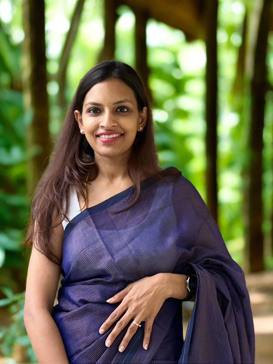 Woman wearing a blue saree standing against a stone wall