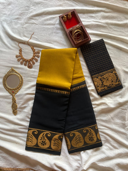 Black and yellow traditional saree with jewelry on a white fabric background
