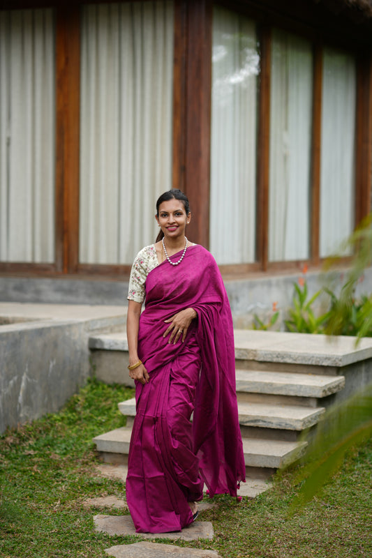 Woman in a pink saree standing on steps outdoors