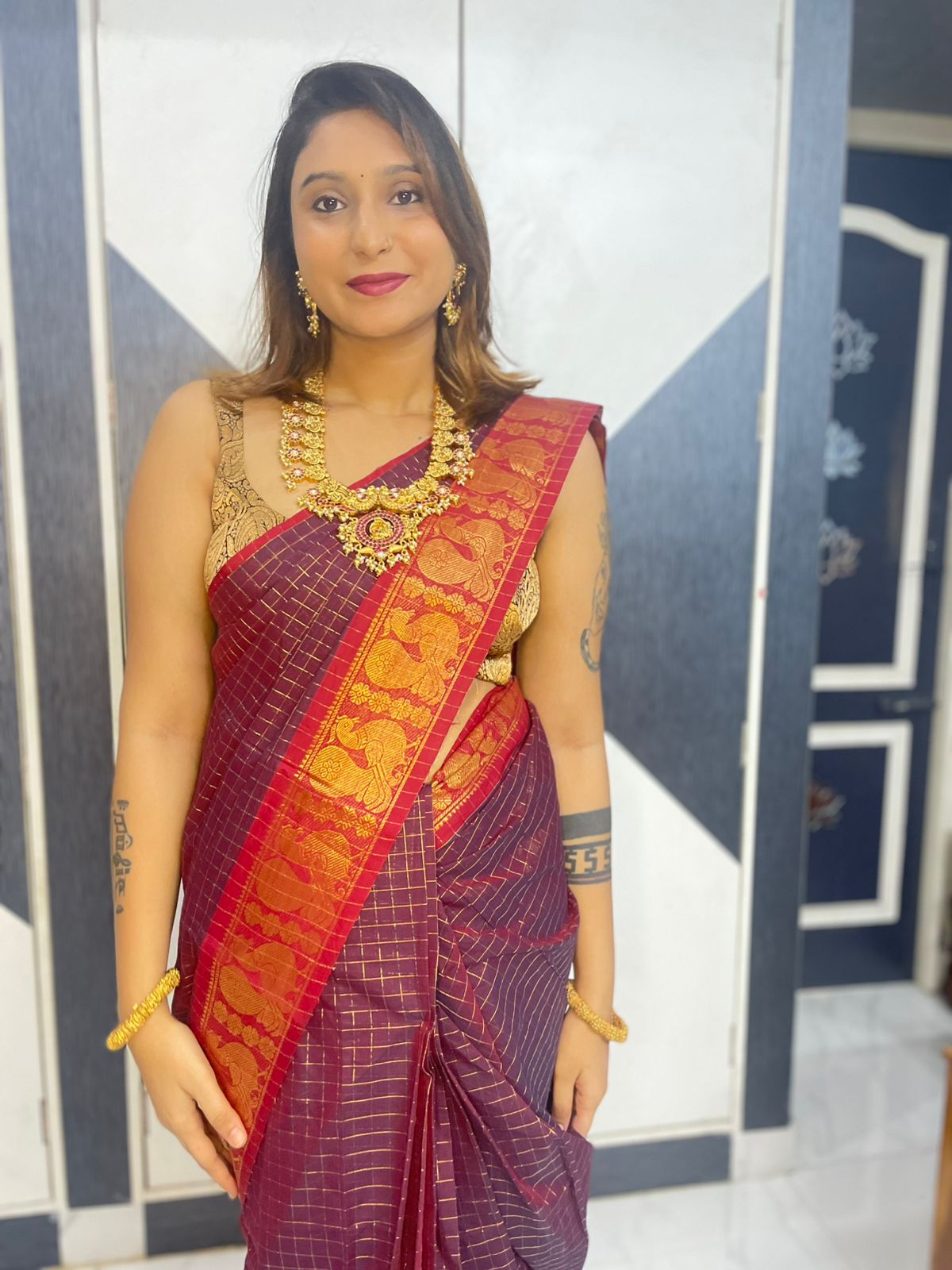 Woman in a traditional maroon saree with gold border indoors