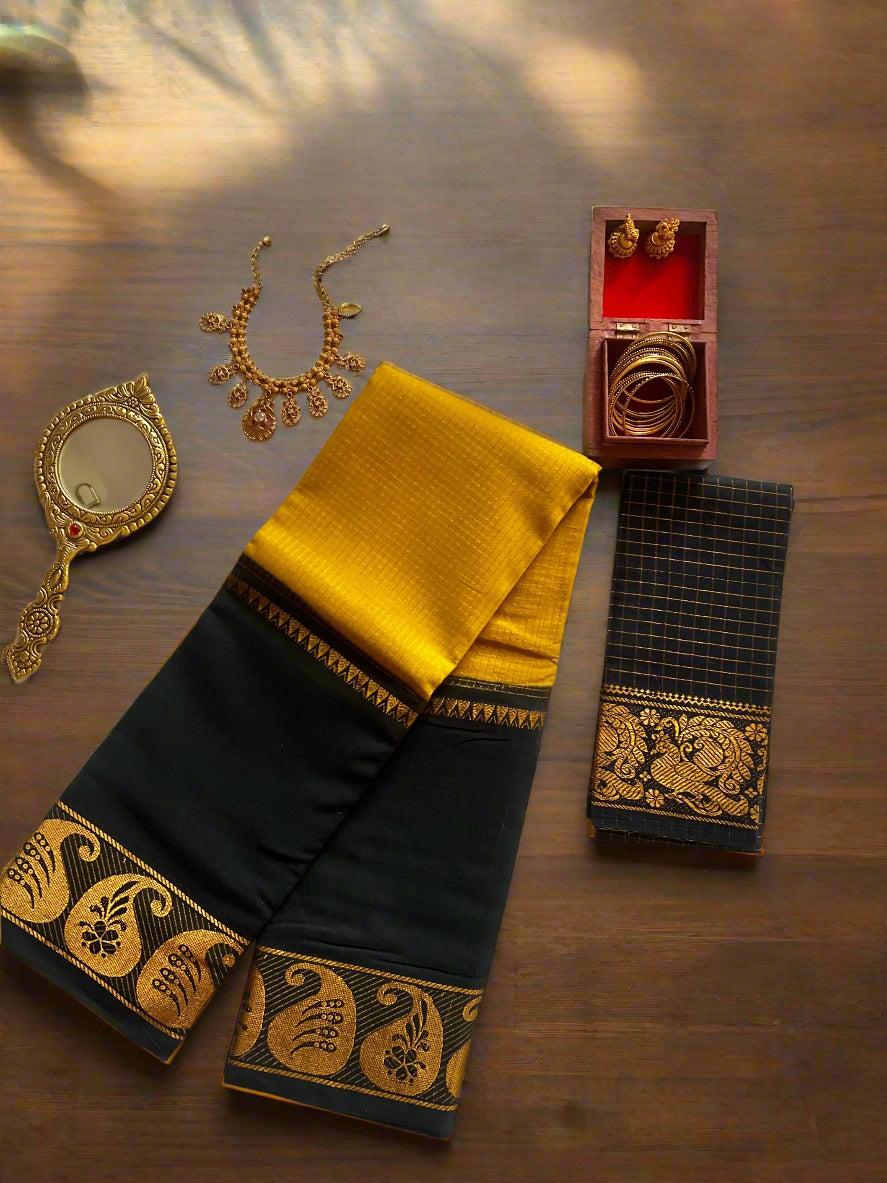 Black and yellow saree with jewelry and a mirror on a white fabric background